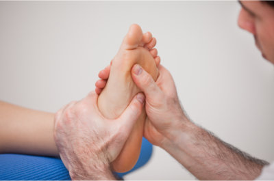 podiatrist practicing reflexology on the foot of woman