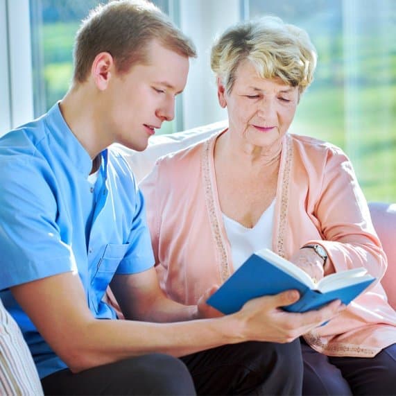 caregiver reading a book to his patient